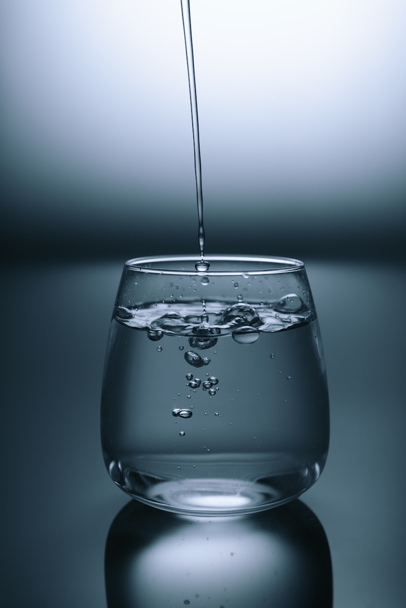 Bicchiere d'acqua limpida su superficie chiara